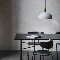 Modern dining set featuring a sleek black table and chairs with a minimalist gray pendant light, showcasing a neutral palette.