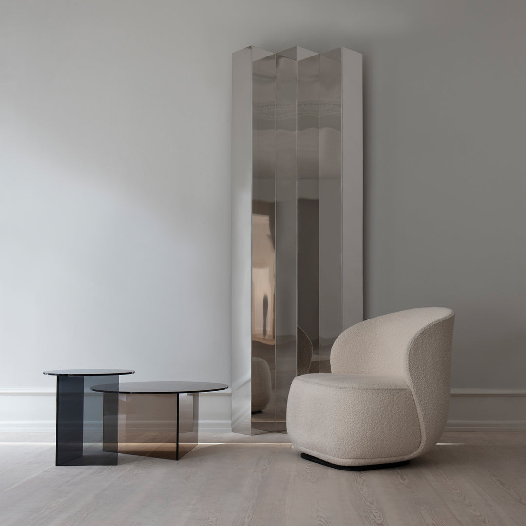 Modern mirror with sleek silver finish and minimalist black glass accent table, set against a soft gray background.