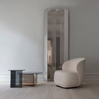 Modern mirror with sleek silver finish and minimalist black glass accent table, set against a soft gray background.
