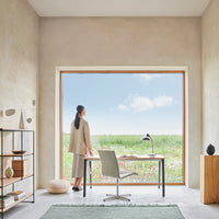 Modern workspace featuring neutral tones, earthy patterns, and a serene landscape view through a large window.