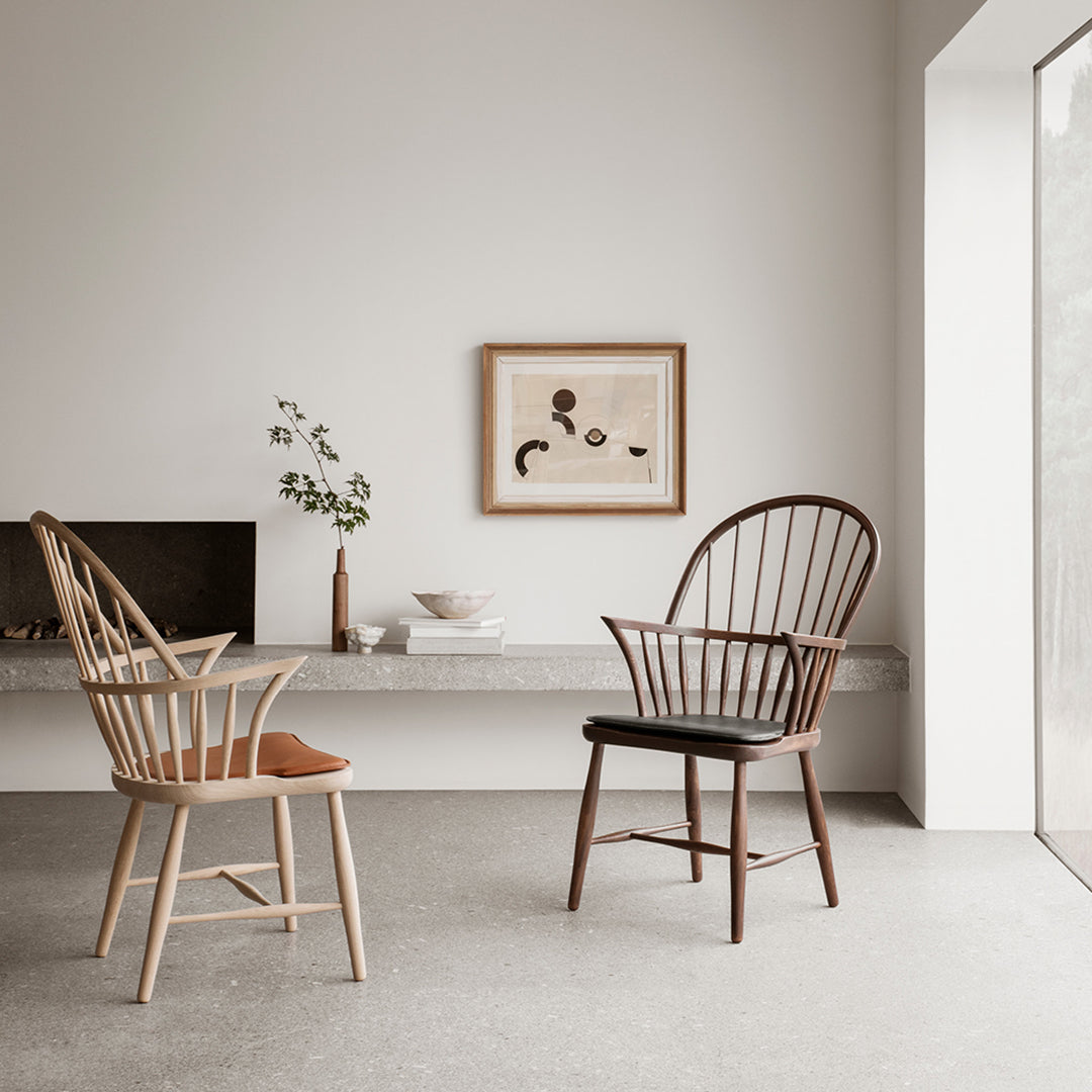 "Two elegant wooden chairs in light and dark hues, featuring a minimalist design and soft curves against a neutral backdrop."