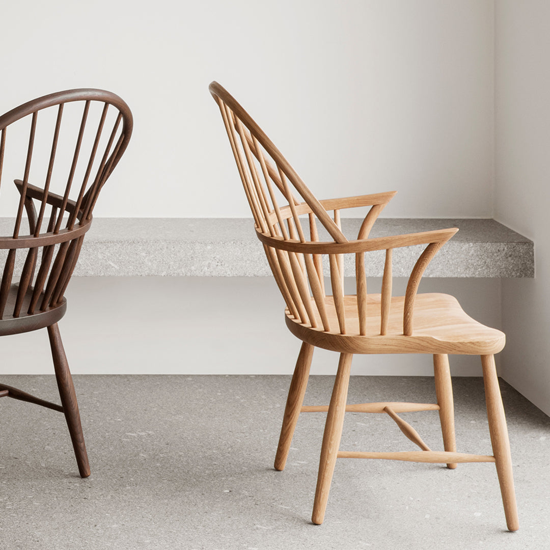 "Two wooden chairs in natural oak and dark brown finishes, showcasing minimalist design and elegant lines."