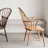 "Two wooden chairs in natural oak and dark brown finishes, showcasing minimalist design and elegant lines."