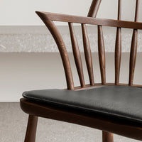"Stylish wooden chair with a dark walnut finish and sleek black leather seat cushion."