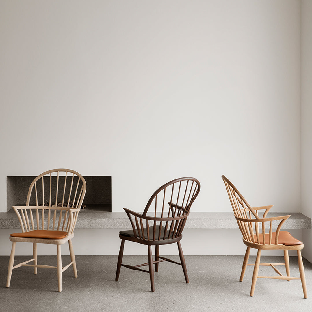 Three chairs featuring natural wood tones: light beige, dark brown, and warm honey, set against a minimalist backdrop.