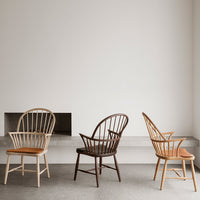 Three chairs featuring natural wood tones: light beige, dark brown, and warm honey, set against a minimalist backdrop.