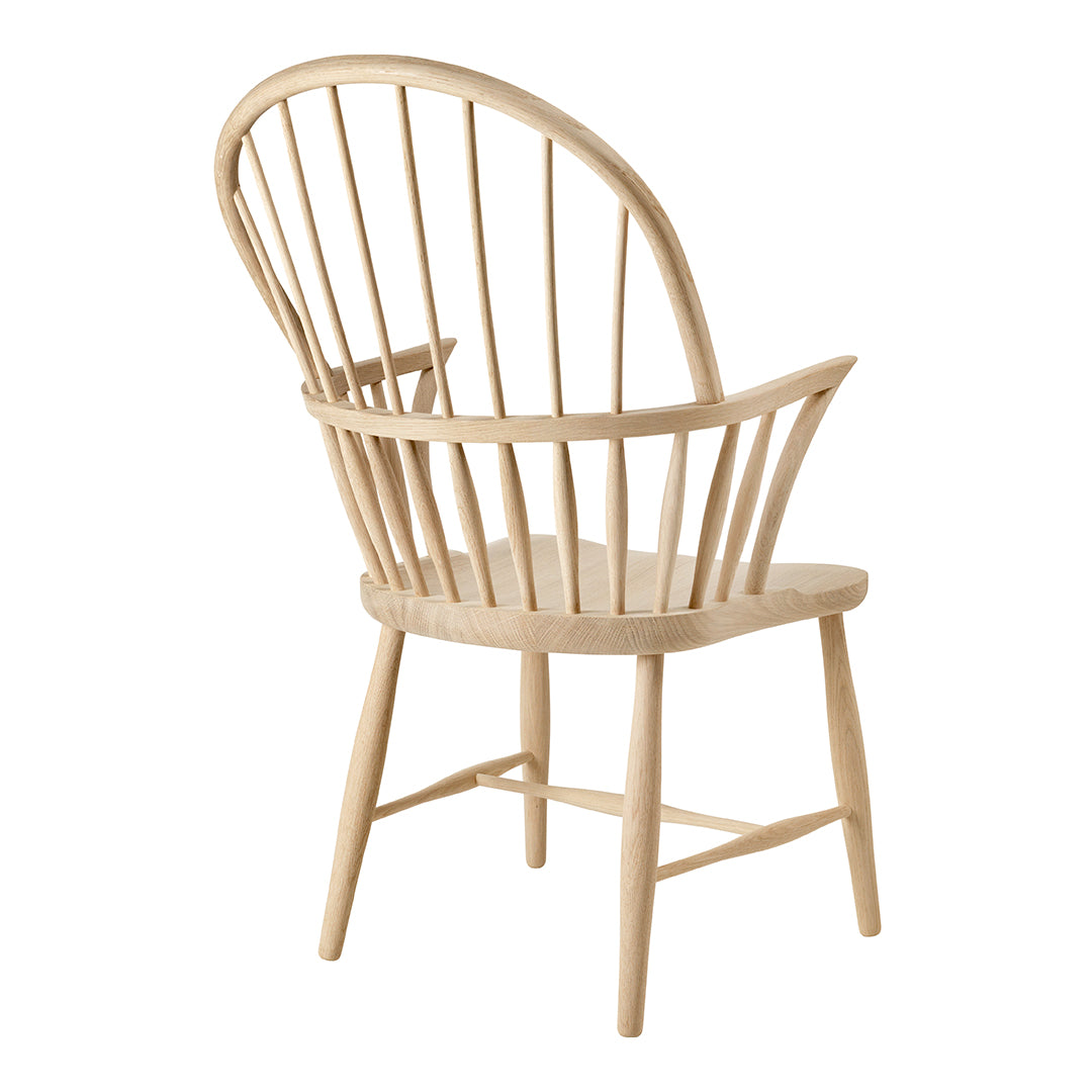 Natural wood chair with a light, smooth finish and distinct vertical spindles, featuring a curved backrest design.