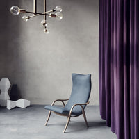 Stylish blue chair with sleek curves, complemented by rich purple curtains and a modern geometric backdrop.