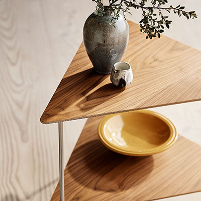 Wooden triangle tabletop with rich brown tones, textured ceramic vase in gray, and vibrant yellow bowl.