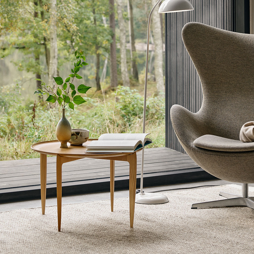 Light wood accent table with a smooth finish, surrounded by neutral tones and natural greenery in a cozy setting.