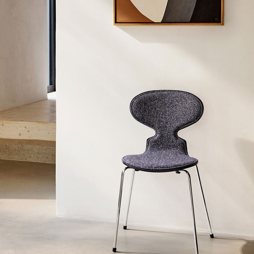 Gray patterned chair with a unique silhouette, complemented by sleek metal legs against a minimalist backdrop.