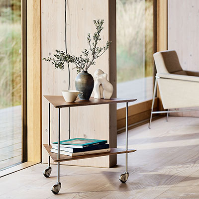 Wooden side table with a natural finish, displaying books and a vase, complemented by a minimalist metal frame.