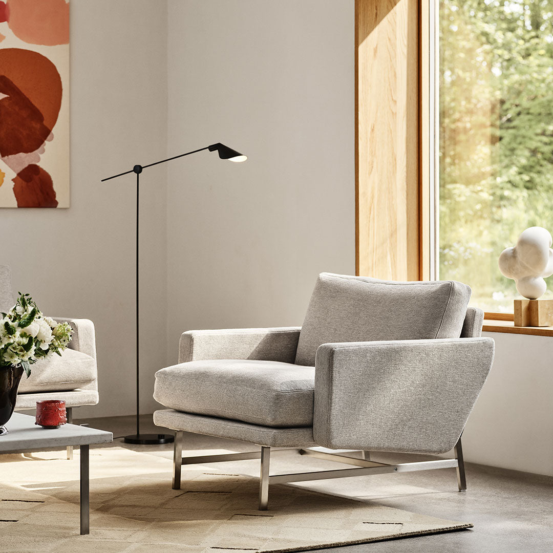 Grey upholstered armchair with a textured pattern, set against a bright, minimalistic room with natural light.