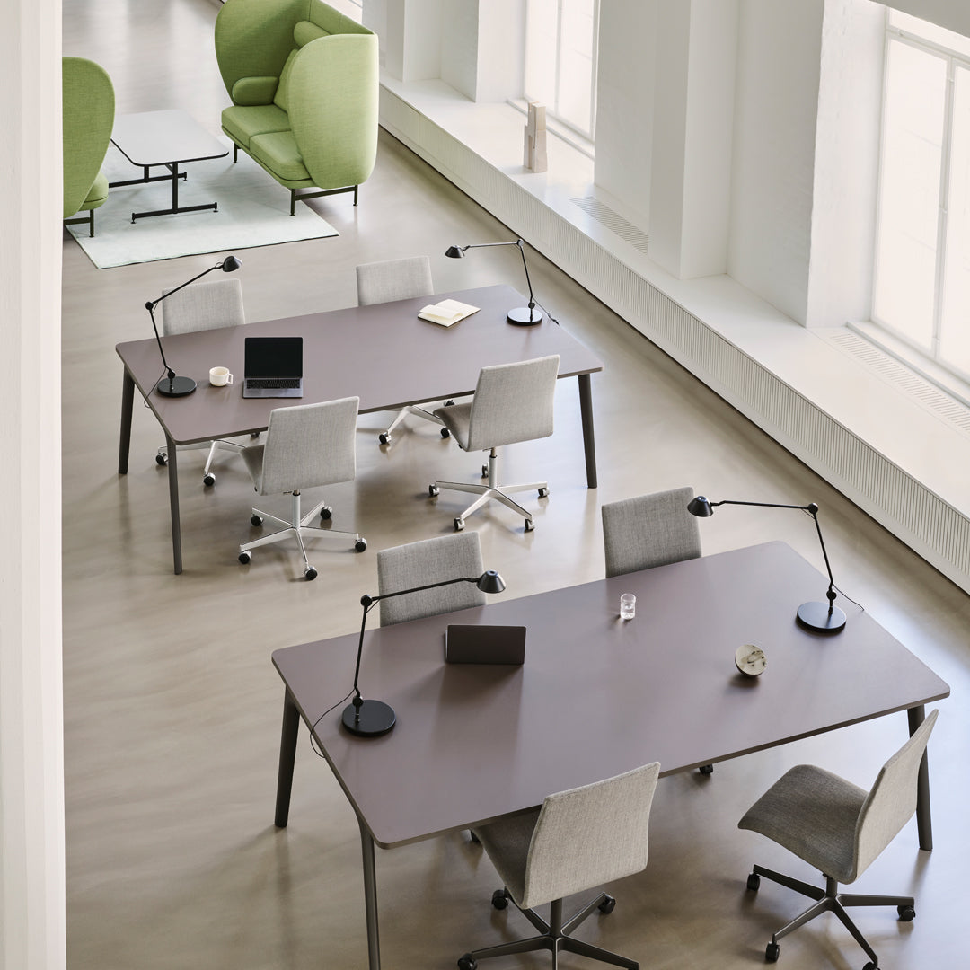 Modern office setup with dark wood tables, gray and beige chairs, and vibrant green armchairs against a light wooden floor.