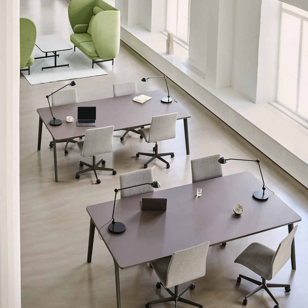 Modern office with beige floors, gray and white chairs, and green accents from the armchairs and plants.