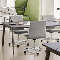 Modern office setting with a dark wood table, light gray chairs, and a vibrant green accent chair.