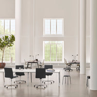 Modern office space featuring black and white furniture against a light grey floor with natural light from large windows.