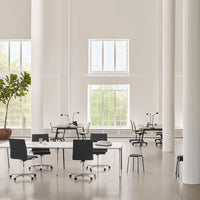 Modern office space featuring light gray walls, white pillars, and black furniture accents. Bright and airy atmosphere.