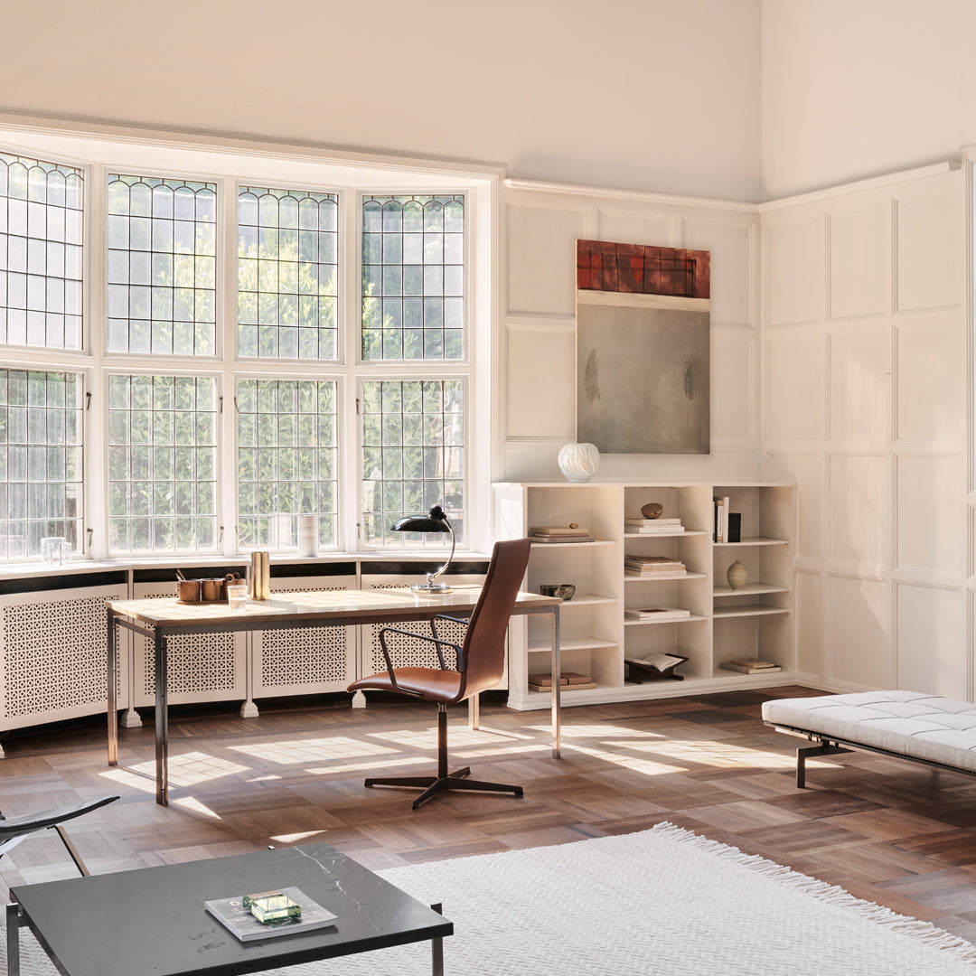Modern workspace with neutral tones, warm wood accents, and a soft white rug, featuring a mix of textures and patterns.