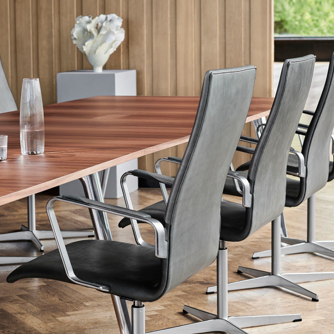 Gray ergonomic chairs with sleek aluminum frames, set against a warm wooden table in a modern office.