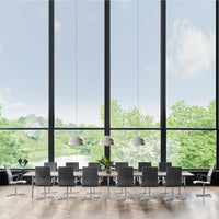 Modern dining table with sleek black chairs and elegant silver accents, set against a backdrop of lush greenery and natural light.