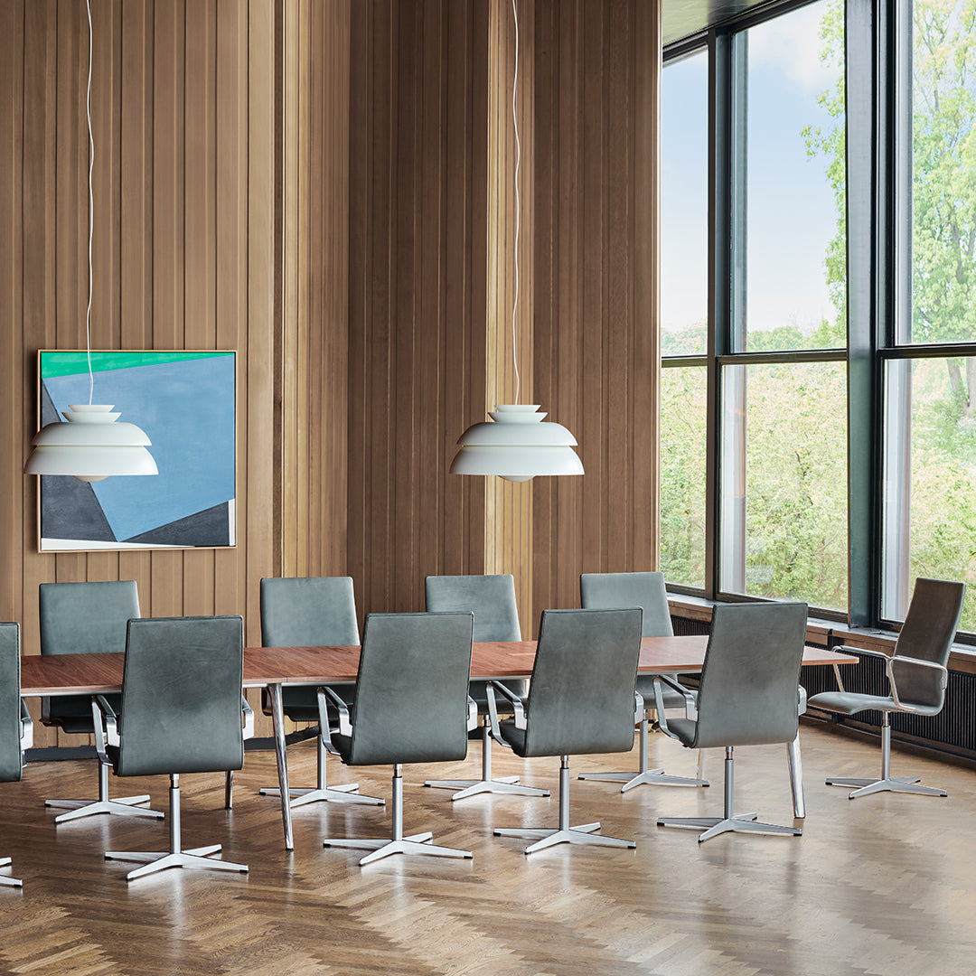 Gray upholstered chairs with sleek chrome bases, set against warm wood paneling and bright natural light. 