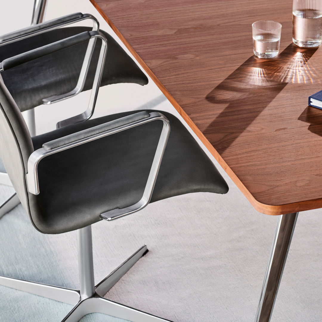 Modern black chairs with sleek silver frames, complemented by a rich wooden tabletop and subtle glass accents.