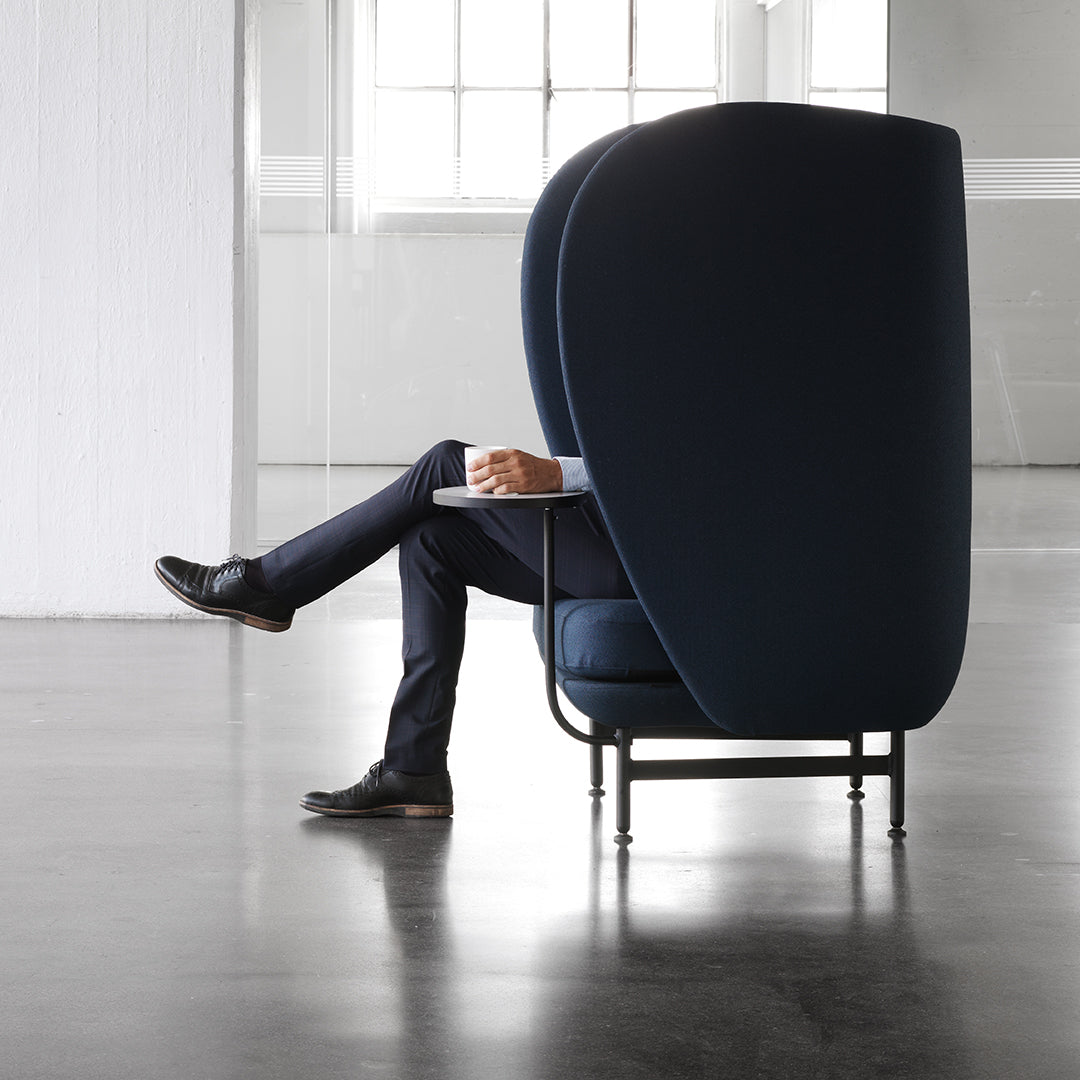 Dark blue upholstered chair with a smooth, curved silhouette and sleek black metal legs. Modern design aesthetic.