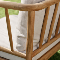 Light tan wooden frame with a textured beige cushion against a vibrant green lawn. Stylish and modern outdoor seating.