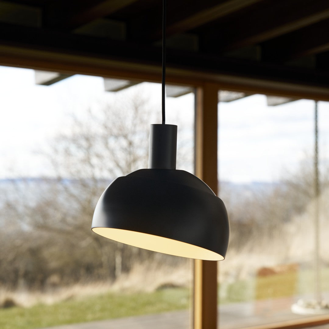 Black pendant light hanging in a room with large windows