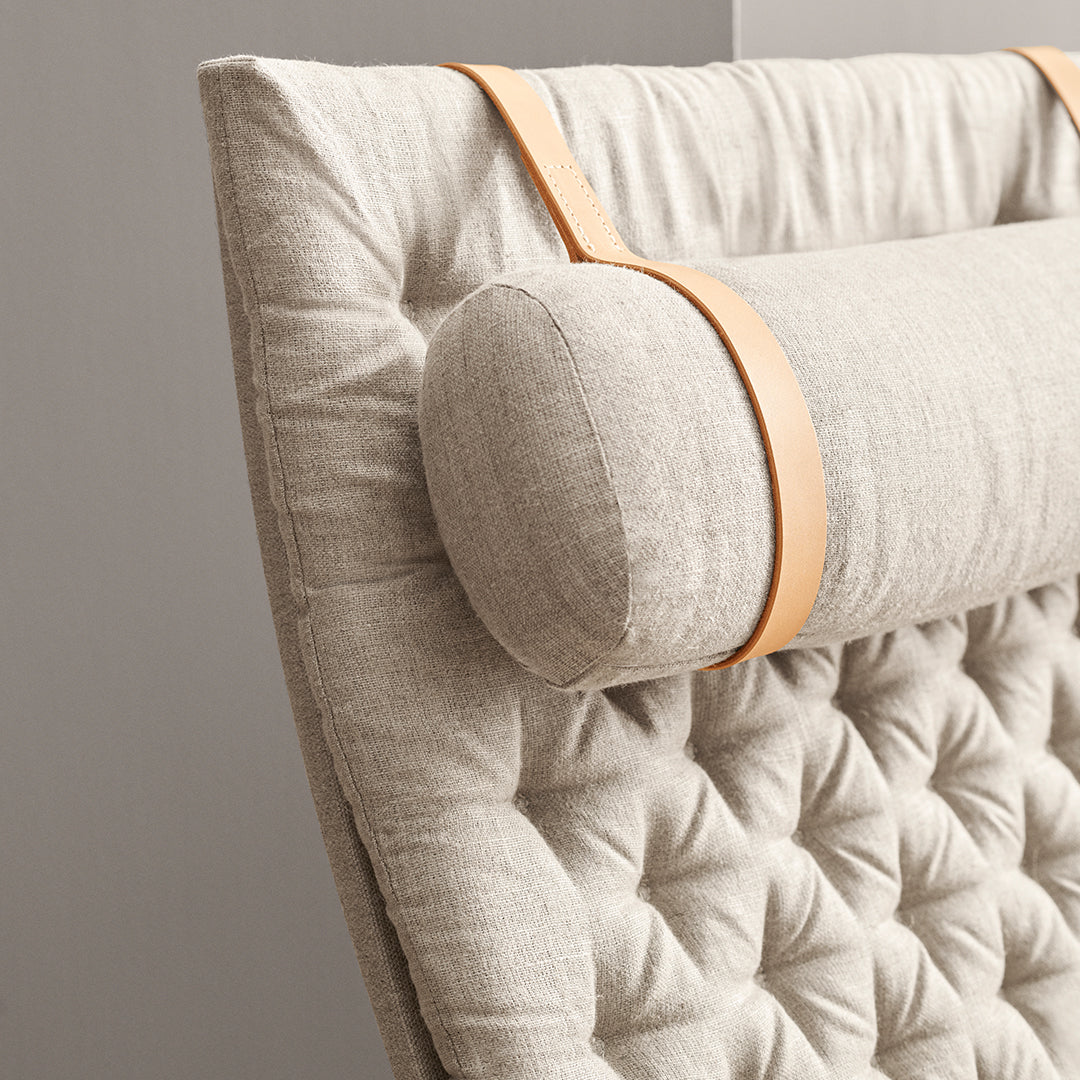Beige tufted upholstery with a smooth light brown leather strap, adding texture and elegance to the design.