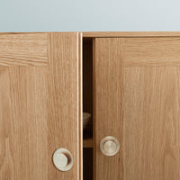 Natural oak wood finish with smooth, minimalist patterns and round knobs, showcasing a warm, light-toned aesthetic.