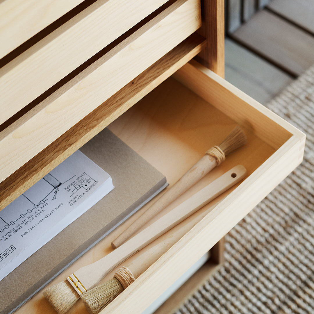 Natural wood tones with a smooth finish, featuring light beige and soft gray accents in a minimalist drawer setup.