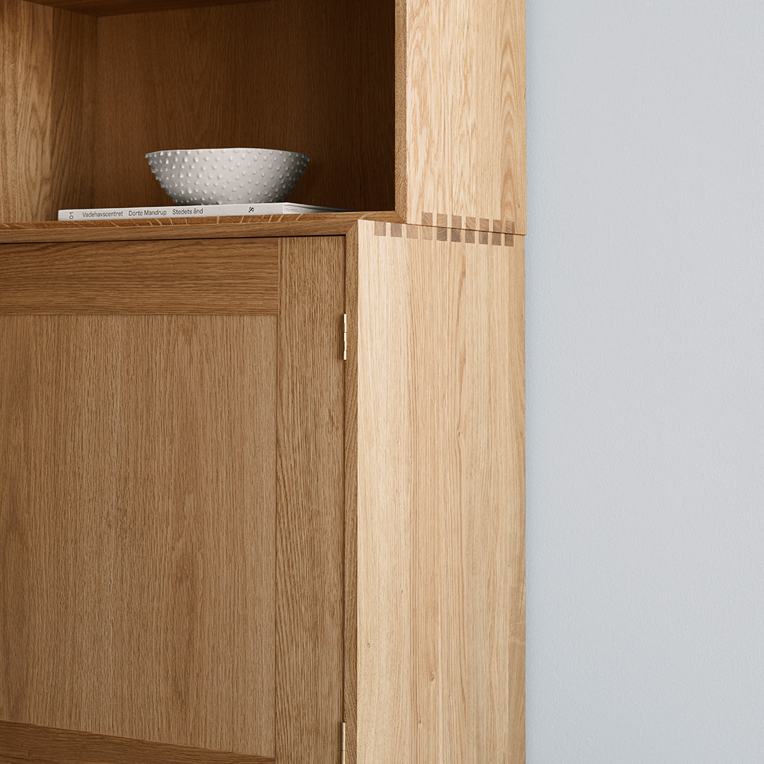Natural oak cabinet with a light wood finish and subtle grain patterns, accented by a minimalist white bowl.