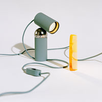 Modern mint green lamp with sleek metallic accents and a vibrant yellow base, featuring a minimalist design and clean lines.