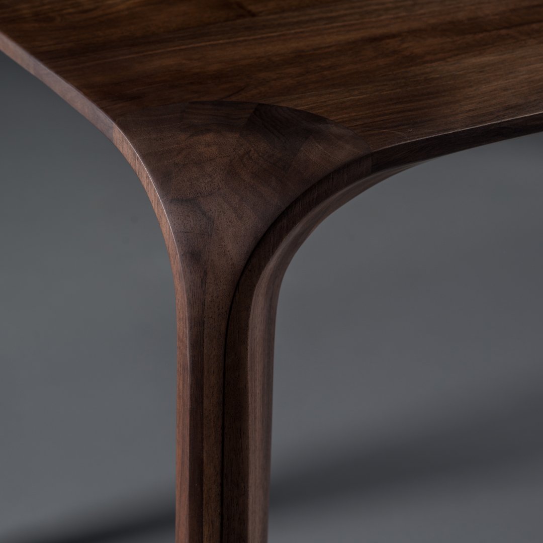 Dark walnut wood finish with smooth, curved edges and a minimalist design against a gray backdrop.