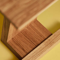 Natural wood grain in warm tones on a minimalist table against a vibrant yellow background.
