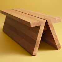 Natural wood bench with a smooth, light brown finish and minimalist design on a vibrant yellow background.