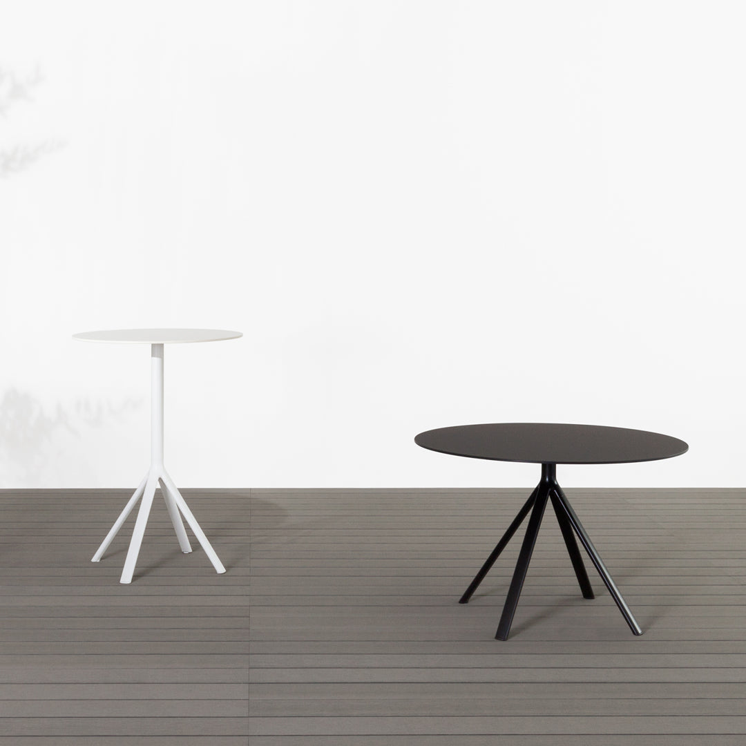 Two modern round tables: one sleek white and one elegant black, featuring geometric tripod legs against a neutral backdrop.