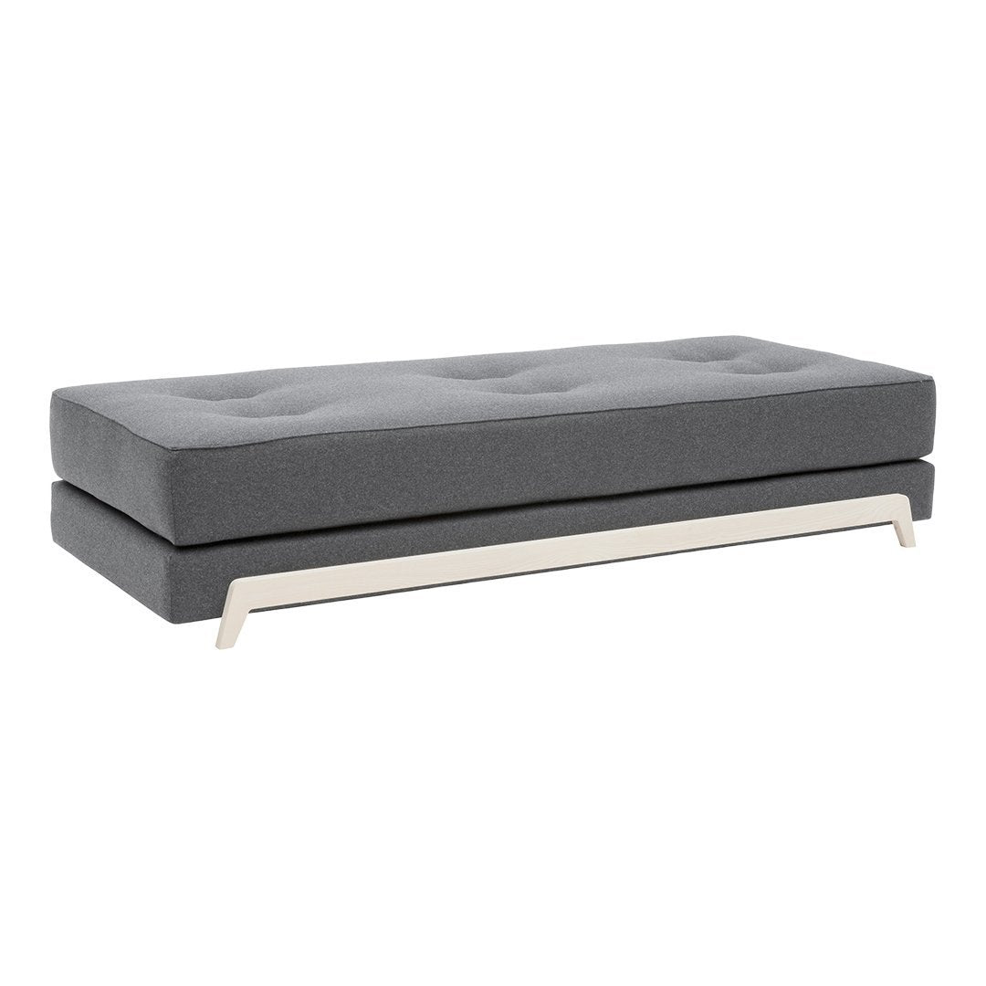 Gray upholstered ottoman with a sleek, modern design and tufted pattern, featuring a stylish silver base.