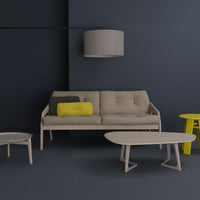 Beige sofa with yellow and green pillows, round and oval beige tables, set against a dark blue wall.