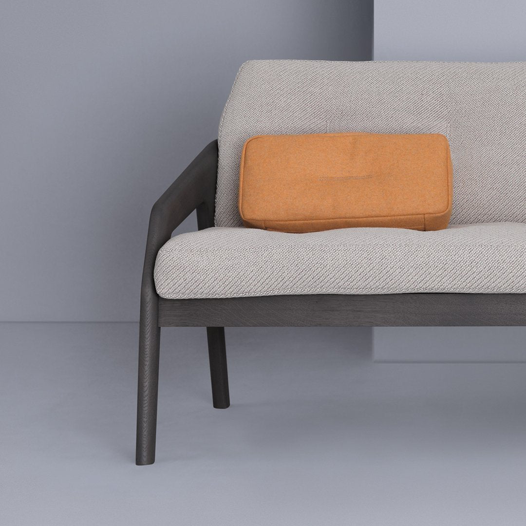 Gray sofa with textured light upholstery and an orange rectangular cushion, minimalist design against a soft gray backdrop.