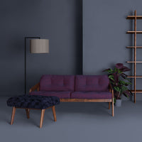 Purple sofa with button detailing, complemented by a dark patterned ottoman against a gray background.