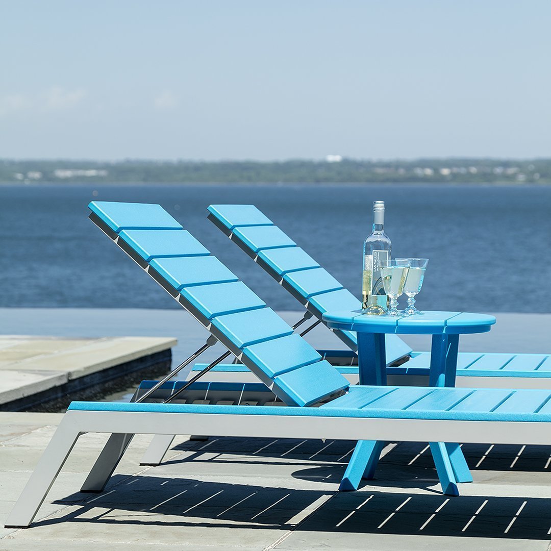 Bright blue lounge chairs paired with a matching circular table, set against a serene water backdrop.