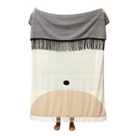 Gray and beige blanket with a whimsical pattern featuring a soft face design and fringe details.