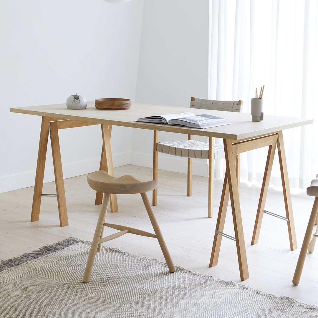 Modern light wood table with a clean, minimalist design. White tabletop complements natural tones in the decor.