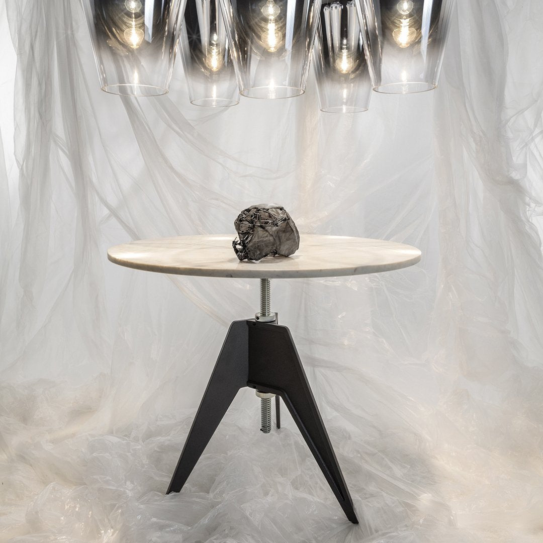 Round white tabletop with a sleek black base, featuring simple, modern lines and a smooth marble pattern.