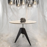 Round white tabletop with a sleek black base, featuring simple, modern lines and a smooth marble pattern.