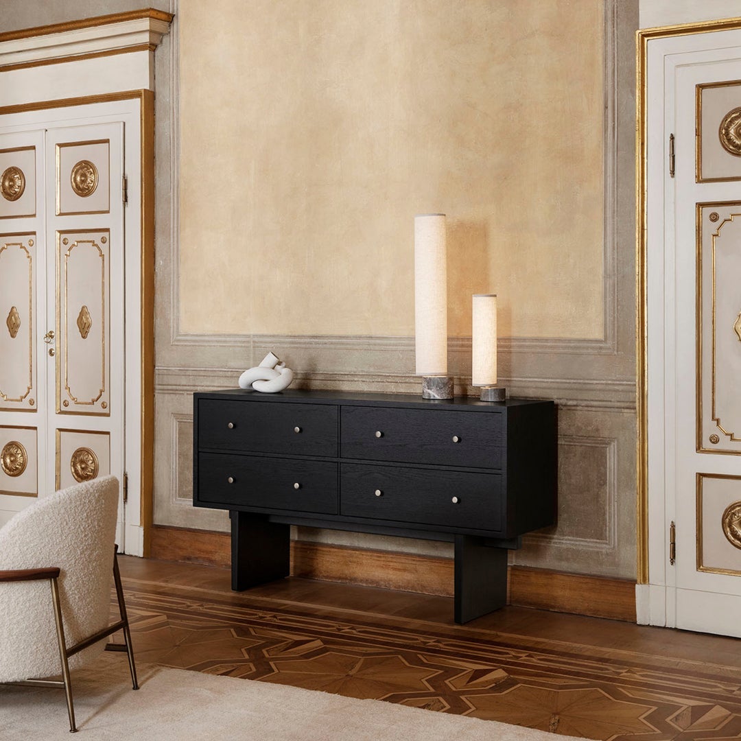 Elegant black sideboard with gold-accented knobs, set against a warm beige wall and rich wooden floor.