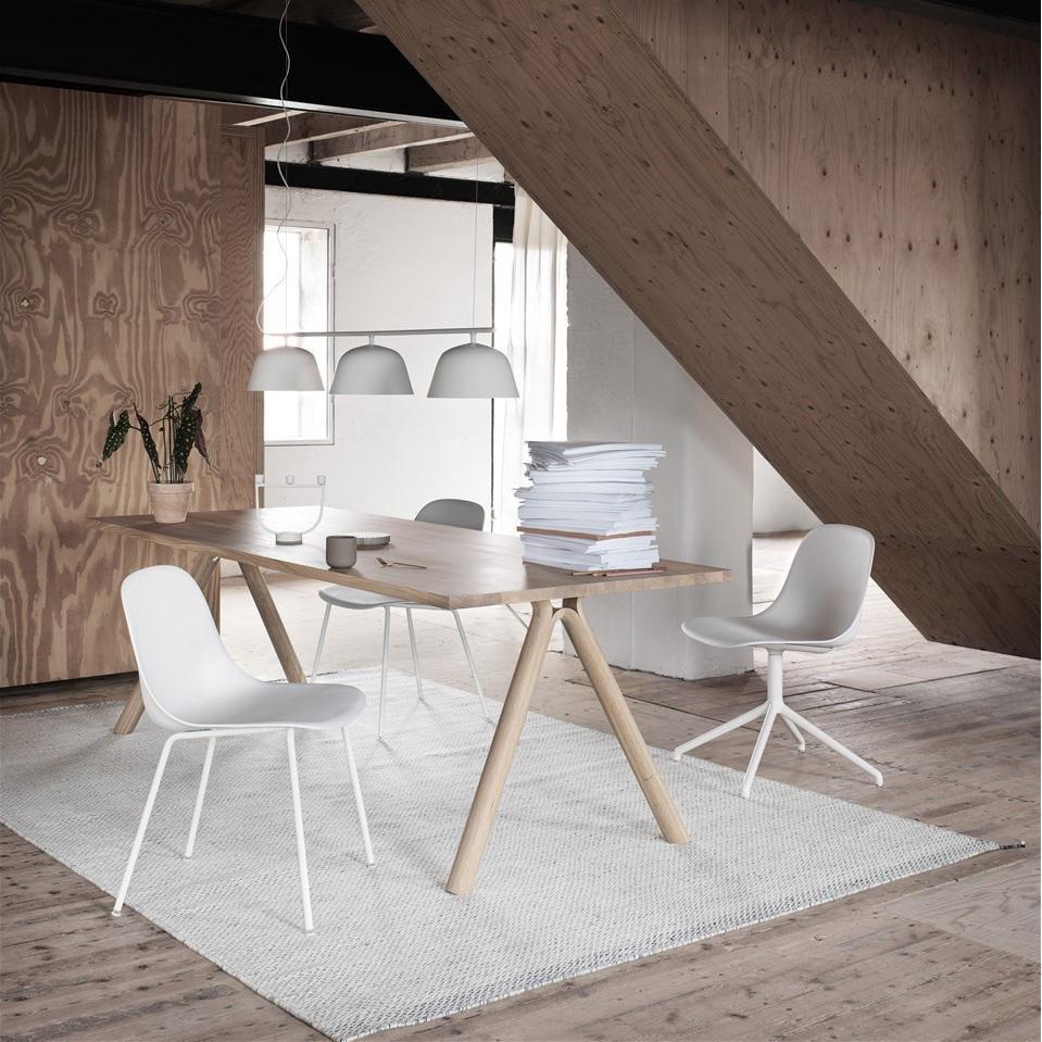 Modern wooden dining table with white chairs, light gray rug, and warm wood accents in a chic, minimalistic interior.